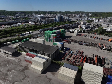 Cincinnati United States 19 April 2026 Aerial view of shipping containers stacked in an industrial yard with warehouses and a factory under a clear blue sky.