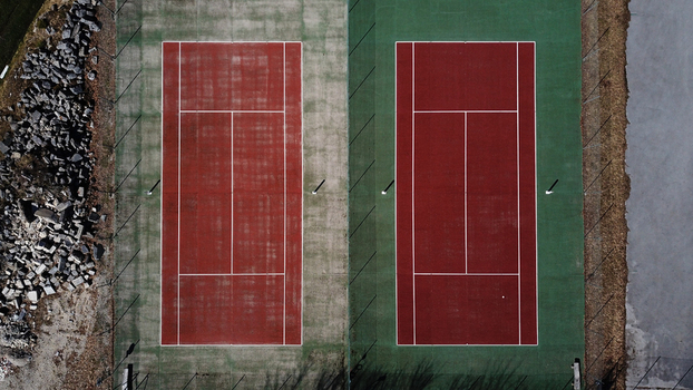 Aerial view of two tennis courts with red and green surfaces situated next to a rocky area in Jougne Bourgogne Franche Comte France. Aerial view of two tennis courts with red and green surfaces situated next to a rocky area in Jougne Bourgogne Franche Comte France.