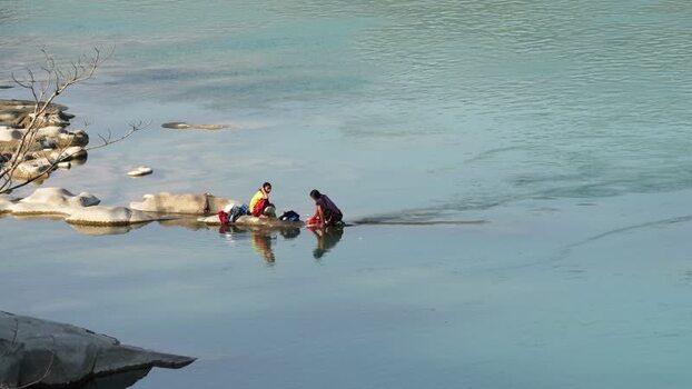 View of people washing clothes in a river in Surkhet Nepal.