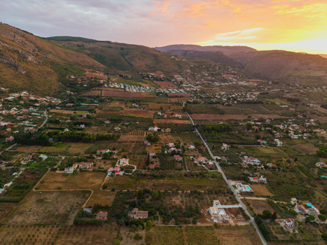Aerial view of the rolling hills and agricultural landscape of Sicily at sunset with scattered houses and olive groves near Palermo Sicily Italy. Aerial view of the rolling hills and agricultural landscape of Sicily at sunset with scattered houses and olive groves near Palermo Sicily Italy.