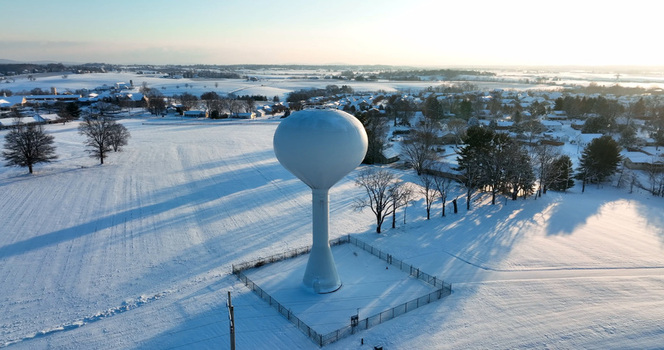 Aerial view of a white water tower standing in a snow covered field in Manheim Pennsylvania United States. Aerial view of a white water tower standing in a snow covered field in Manheim Pennsylvania United States.