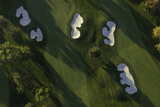 Aerial view of a golf course in autumn with sand bunkers green fairways and trees casting long shadows in Glenview Illinois United States. Aerial view of a golf course in autumn with sand bunkers green fairways and trees casting long shadows in Glenview Illinois United States.