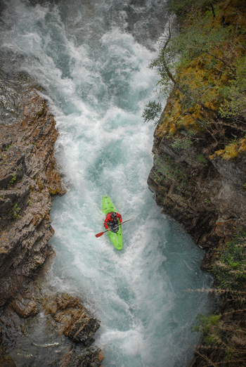View of a kayaker in a green kayak navigating the white water rapids of the Rio Manso canyon San Carlos de Bariloche Rio Negro Argentina. View of a kayaker in a green kayak navigating the white water rapids of the Rio Manso canyon San Carlos de Bariloche Rio Negro Argentina.
