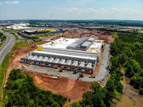 Aerial view of a large data center construction site with heavy machinery exposed earth and surrounding forest in Ashburn Virginia United States. Aerial view of a large data center construction site with heavy machinery exposed earth and surrounding forest in Ashburn Virginia United States.