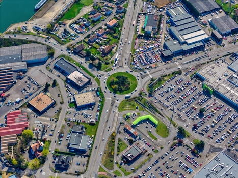 Aerial view of a bustling roundabout amidst commercial buildings and parking lots a vibrant tableau of urban activity unfolding from above Sausheim Grand Est France.