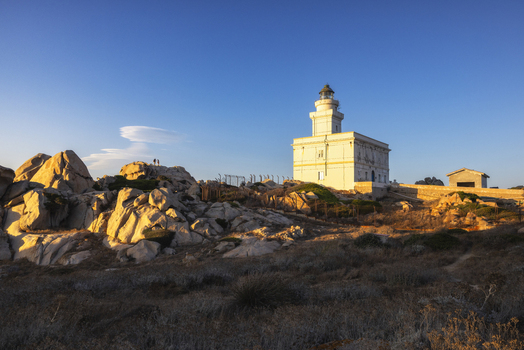 View of the historic Capo Testa lighthouse standing on granite rock formations under a clear blue sky during golden hour Capo Testa Sardegna Italy. View of the historic Capo Testa lighthouse standing on granite rock formations under a clear blue sky during golden hour Capo Testa Sardegna Italy.