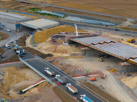 Aerial view of the Black Cat Roundabout highway construction site with bridge infrastructure heavy machinery and trucks in Chawston England United Kingdom. Aerial view of the Black Cat Roundabout highway construction site with bridge infrastructure heavy machinery and trucks in Chawston England United Kingdom.