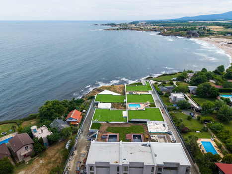 Aerial view of a modern coastal property featuring green roofs swimming pools and landscaped terraces overlooking the Black Sea in Lozenets Burgas Bulgaria.