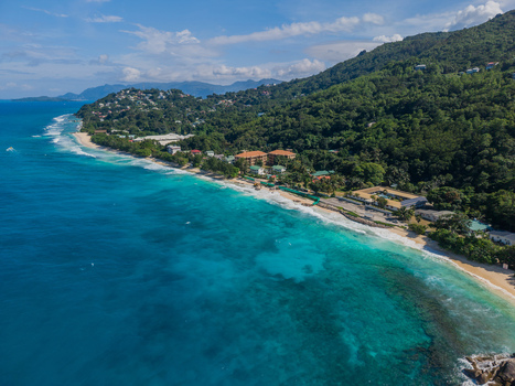 Aerial view of turquoise waters meet a pristine beach fringed by lush green hills in a tropical paradise La Retraite Mahe Island Seychelles. Aerial view of turquoise waters meet a pristine beach fringed by lush green hills in a tropical paradise La Retraite Mahe Island Seychelles.