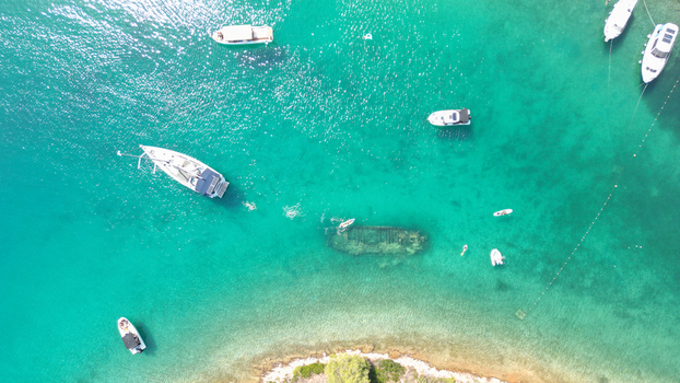 Aerial view of the Kontesa shipwreck submerged in turquoise waters with anchored boats and people swimming in Necujam Split Dalmatia County Croatia. Aerial view of the Kontesa shipwreck submerged in turquoise waters with anchored boats and people swimming in Necujam Split Dalmatia County Croatia.