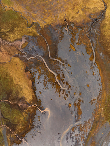 Aerial view of Kviarjokull glacial river system with braided channels and sediment flowing through mossy terrain in Sveitarfelagid Hornafjordur Iceland.