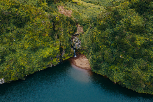 Aerial view of Caldeira Funda waterfall cascading into a deep blue lagoon surrounded by lush green volcanic cliffs in Lajes das Flores Azores Portugal. Aerial view of Caldeira Funda waterfall cascading into a deep blue lagoon surrounded by lush green volcanic cliffs in Lajes das Flores Azores Portugal.