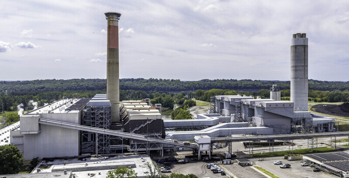 Aerial view of Gallatin Fossil Plant coal fired power station with tall chimneys and industrial buildings set against a backdrop of lush green trees Gallatin TN United States.