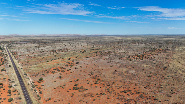Aerial view of a long road stretches across the arid landscape contrasting with the rusty earth and sparse greenery Karoo Desert Northern Cape South Africa. Aerial view of a long road stretches across the arid landscape contrasting with the rusty earth and sparse greenery Karoo Desert Northern Cape South Africa.