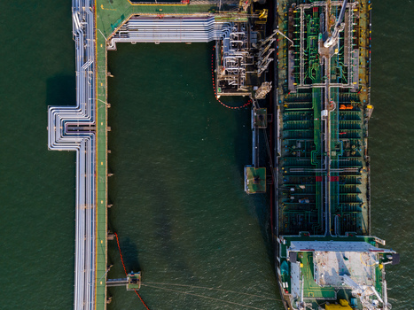 Aerial view of an oil tanker docked at a terminal with industrial pipelines and storage infrastructure in Cilacap Regency Central Java Indonesia. Aerial view of an oil tanker docked at a terminal with industrial pipelines and storage infrastructure in Cilacap Regency Central Java Indonesia.