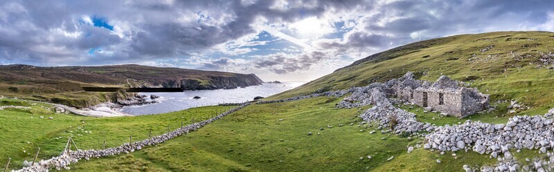 Aerial view of the historic stone ruins at An Port surrounded by lush green hills dry stone walls and the rugged coastline of the Atlantic Ocean in Ardara County Donegal Ireland.