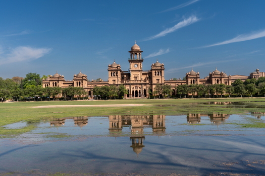 View of the historic Islamia College University Peshawar with its reflection in a flooded lawn under a clear blue sky in Peshawar Khyber Pakhtunkhwa Pakistan. View of the historic Islamia College University Peshawar with its reflection in a flooded lawn under a clear blue sky in Peshawar Khyber Pakhtunkhwa Pakistan.