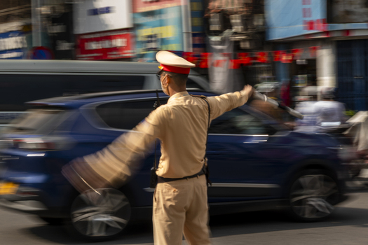 View of a traffic police officer in uniform directing vehicles on a busy street in Hanoi Ha Noi Vietnam.