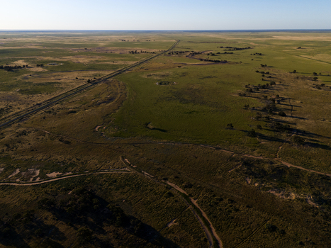 Aerial view of the vast flat landscape of the Australian outback with a long straight road stretching across the arid plains near Hay New South Wales Australia.