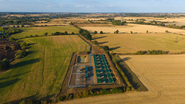 Aerial view of Battery Energy Storage System Grendon featuring rows of green energy storage containers and electrical infrastructure in rural farmland in Northampton England United Kingdom. Aerial view of Battery Energy Storage System Grendon featuring rows of green energy storage containers and electrical infrastructure in rural farmland in Northampton England United Kingdom.