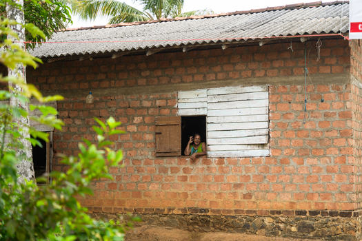Sri Lanka 19 February 2026 View of a woman looking out of a window of a traditional brick house surrounded by lush tropical greenery.