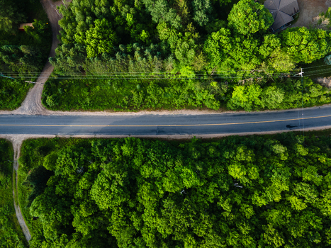 Aerial view of a paved road cutting through dense green forest near Commanda Lake in Restoule Ontario Canada. Aerial view of a paved road cutting through dense green forest near Commanda Lake in Restoule Ontario Canada.