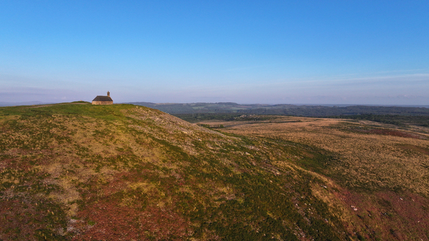 Aerial view of Chapelle Saint Michel de Brasparts on a grassy hilltop overlooking the vast moorland of the Monts d Arree under a clear blue sky Saint Rivoal Bretagne France. Aerial view of Chapelle Saint Michel de Brasparts on a grassy hilltop overlooking the vast moorland of the Monts d Arree under a clear blue sky Saint Rivoal Bretagne France.