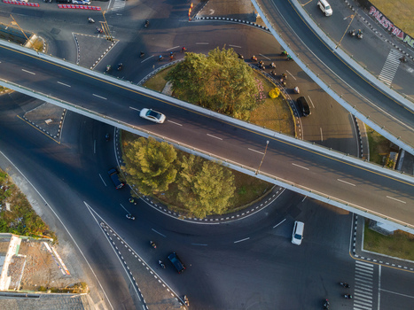 Aerial view of a busy roundabout with an overpass featuring flowing traffic cars and motorcycles surrounded by lush trees in Yogyakarta Special Region of Yogyakarta Indonesia. Aerial view of a busy roundabout with an overpass featuring flowing traffic cars and motorcycles surrounded by lush trees in Yogyakarta Special Region of Yogyakarta Indonesia.