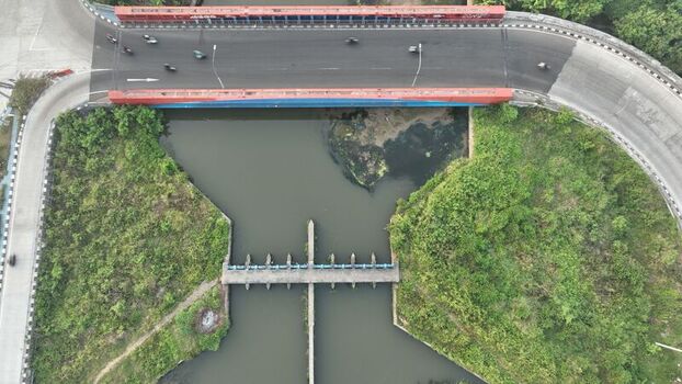 Aerial view of a road bridge crossing a river with a weir structure surrounded by lush green vegetation in Bekasi Barat West Java Indonesia. Aerial view of a road bridge crossing a river with a weir structure surrounded by lush green vegetation in Bekasi Barat West Java Indonesia.