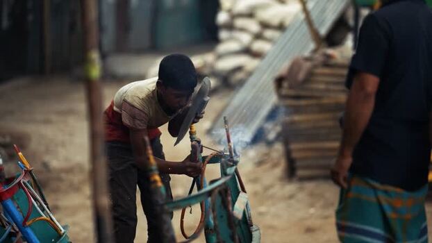 View of a young boy welding metal in Aminbazar Bangladesh. View of a young boy welding metal in Aminbazar Bangladesh.