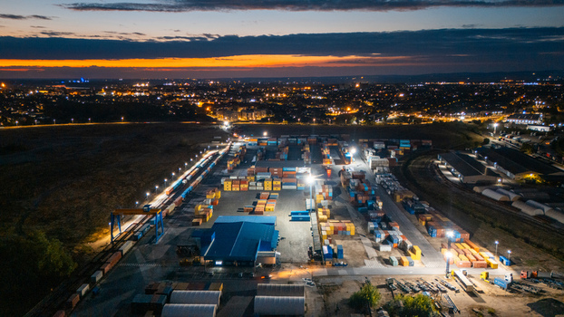 Aerial view of RTC Luka Leget logistics facility with shipping containers cranes and railway tracks illuminated at dusk in Sremska Mitrovica Vojvodina Serbia. Aerial view of RTC Luka Leget logistics facility with shipping containers cranes and railway tracks illuminated at dusk in Sremska Mitrovica Vojvodina Serbia.