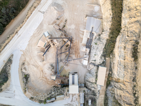 Aerial view of a stone quarry with industrial processing machinery conveyor belts and piles of gravel in Teulada Valencian Community Spain.