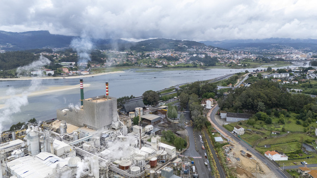 Aerial view of the Biofabrica de Ence industrial complex with smoking chimneys near the river estuary and green hills in Pontevedra Pontevedra Spain. Aerial view of the Biofabrica de Ence industrial complex with smoking chimneys near the river estuary and green hills in Pontevedra Pontevedra Spain.