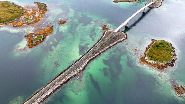 Aerial view of the bridge connecting small rocky islands in the Lofoten archipelago surrounded by turquoise waters in Nordland Norway.