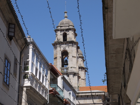 View of the historic bell tower of the Concatedral Basilica de Santa Maria de Vigo rising above narrow streets with traditional buildings and string lights in Vigo Pontevedra Spain. View of the historic bell tower of the Concatedral Basilica de Santa Maria de Vigo rising above narrow streets with traditional buildings and string lights in Vigo Pontevedra Spain.
