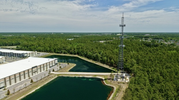 Aerial view of a tall telecommunications tower standing beside industrial warehouses artificial ponds and a dense green forest in World Golf Village Florida United States. Aerial view of a tall telecommunications tower standing beside industrial warehouses artificial ponds and a dense green forest in World Golf Village Florida United States.