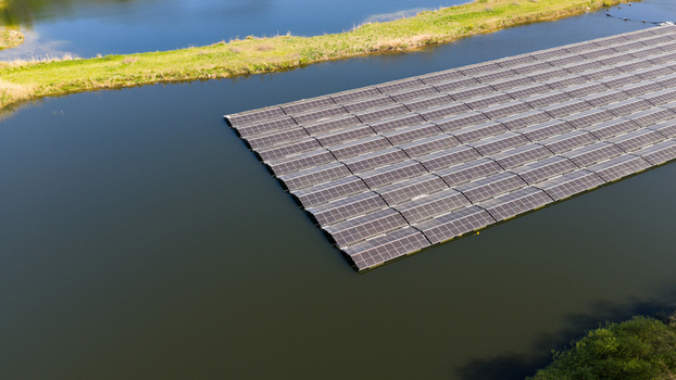 Aerial view of a floating solar farm with rows of photovoltaic panels on a calm lake surrounded by green grassy banks in Zwolle Overijssel Netherlands. Aerial view of a floating solar farm with rows of photovoltaic panels on a calm lake surrounded by green grassy banks in Zwolle Overijssel Netherlands.