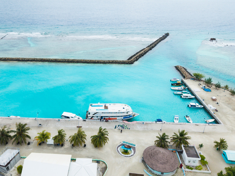 Aerial view of turquoise waters meet the land at the harbor with boats docked creating a vibrant contrast against the tropical greenery Vashafaru Island Maldives. Aerial view of turquoise waters meet the land at the harbor with boats docked creating a vibrant contrast against the tropical greenery Vashafaru Island Maldives.