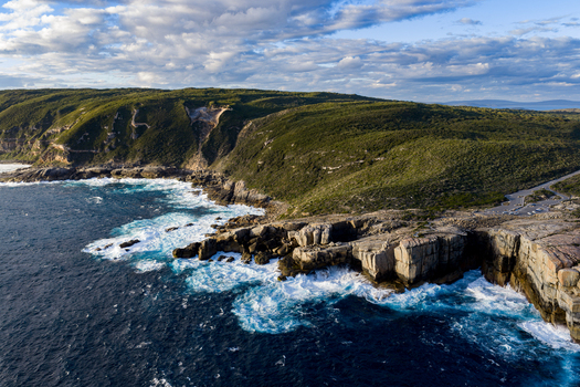 Aerial view of The Gap a dramatic rock formation on the rugged coastline with crashing waves deep blue ocean and lush green vegetation in Torndirrup Western Australia Australia. Aerial view of The Gap a dramatic rock formation on the rugged coastline with crashing waves deep blue ocean and lush green vegetation in Torndirrup Western Australia Australia.