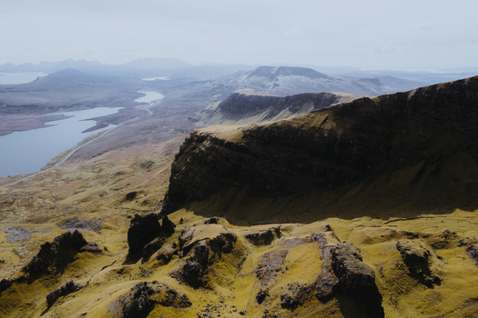 Aerial view of The Storr with its dramatic rocky cliffs and grassy slopes overlooking the rugged landscape and distant loch in Portree Scotland United Kingdom. Aerial view of The Storr with its dramatic rocky cliffs and grassy slopes overlooking the rugged landscape and distant loch in Portree Scotland United Kingdom.
