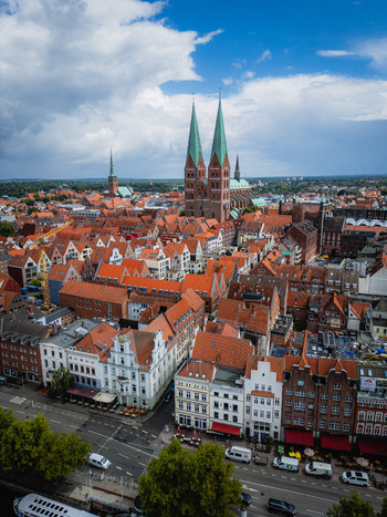 Aerial view of the striking twin spires of the Marienkirche rise above the old town s red tiled roofs framed by a vibrant sky L&uuml;beck Schleswig Holstein Germany.