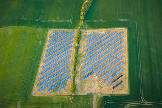 Aerial view of a solar panel farm surrounded by lush green agricultural fields and a line of trees Chvalkovice Hradec Kralove Region Czechia.
