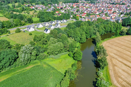 Aerial view of the Regnitzaltwasser river surrounded by lush green trees and residential houses in Forchheim Bayern Germany. Aerial view of the Regnitzaltwasser river surrounded by lush green trees and residential houses in Forchheim Bayern Germany.