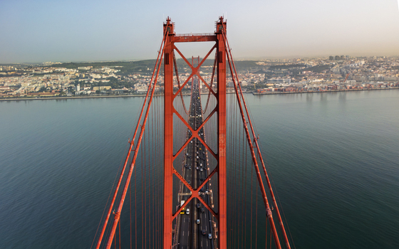 Aerial view of the 25 de Abril Bridge spanning the Tagus River with traffic flowing across the red suspension structure Lisbon Lisbon Portugal.
