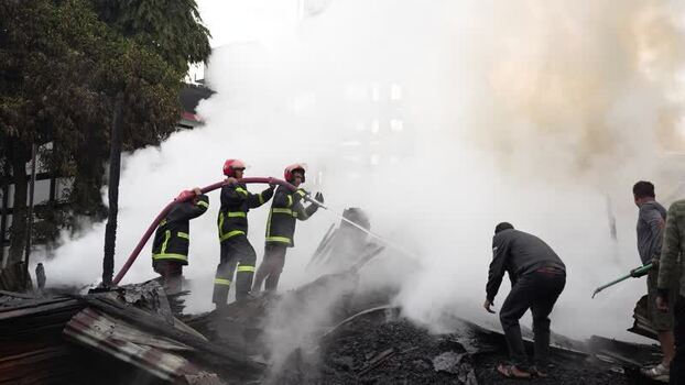 View of firefighters battling a fire amidst thick smoke in Bangladesh. View of firefighters battling a fire amidst thick smoke in Bangladesh.