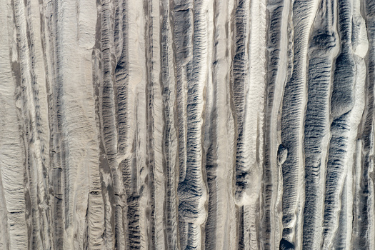 Aerial view of the textured eroded landscape of the Tagebau Welzow Sud brown coal open pit mine showing deep vertical gullies and sediment layers in Spremberg Brandenburg Germany. Aerial view of the textured eroded landscape of the Tagebau Welzow Sud brown coal open pit mine showing deep vertical gullies and sediment layers in Spremberg Brandenburg Germany.