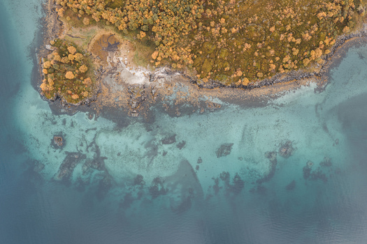 Aerial view of the rugged Lofoten coastline with turquoise waters rocky shores and autumn colored vegetation near Leknes Nordland Norway. Aerial view of the rugged Lofoten coastline with turquoise waters rocky shores and autumn colored vegetation near Leknes Nordland Norway.