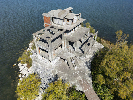 Aerial view of an unfinished concrete building on a small peninsula surrounded by the waters of Lake Shkodra in Shiroka Shkoder County Albania. Aerial view of an unfinished concrete building on a small peninsula surrounded by the waters of Lake Shkodra in Shiroka Shkoder County Albania.