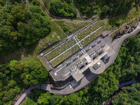 Aerial view of the Verzasca Dam power station infrastructure with electrical transformers and equipment surrounded by dense green forest Gordola Ticino Switzerland. Aerial view of the Verzasca Dam power station infrastructure with electrical transformers and equipment surrounded by dense green forest Gordola Ticino Switzerland.