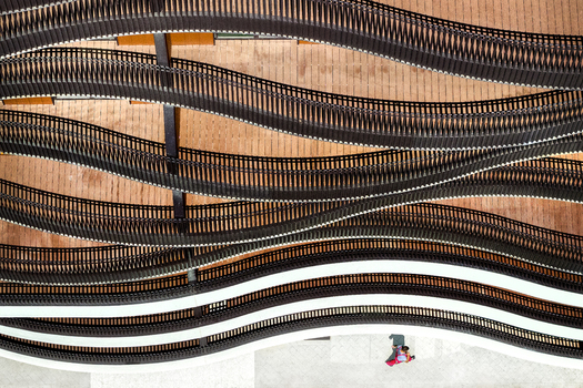 Aerial view of modern building architecture featuring wavy black railings and wooden decking with a person walking below in Belgrade City of Belgrade Serbia. Aerial view of modern building architecture featuring wavy black railings and wooden decking with a person walking below in Belgrade City of Belgrade Serbia.